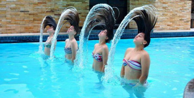 cuatro chicas saliendo del agua, moviéndose el cabello en sincronización