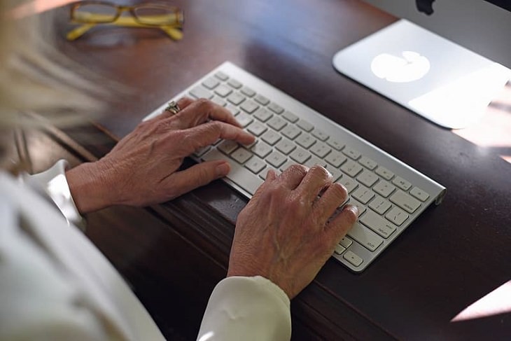Keyboard shortcuts for the ‘Control’ (‘Ctrl’) key, older woman with blonde hair wearing white shirt using a white keyboard