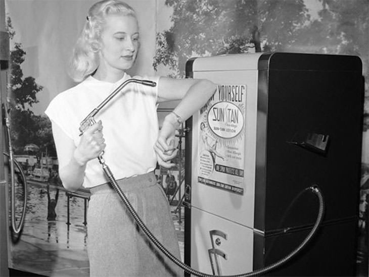 Prácticas De Belleza Del Pasado Mujer que usa una máquina expendedora de bronceado, 1949