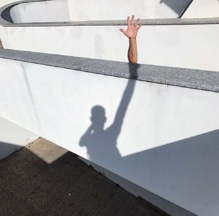 IImágenes De Ilusiones Ópticas De Tiago Silva hombre simula con sombra levantar la mano muy alto