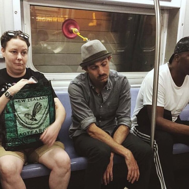 Imágenes divertidas en el metro un hombre sujetando su sombrero a un destapacaños