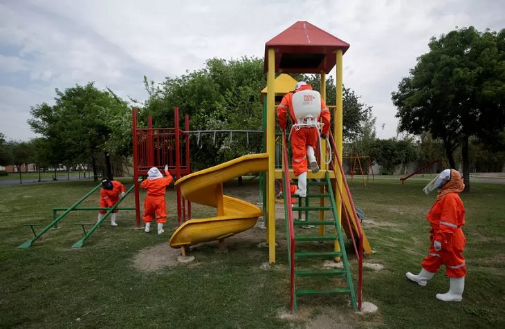 Trabajadores del municipio desinfectando los juegos infantiles de un parque en México