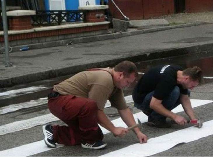 Divertidas Fotografías De La Vida Cotidiana En Rusia dos hombres pegando las líneas para cruzar la calle