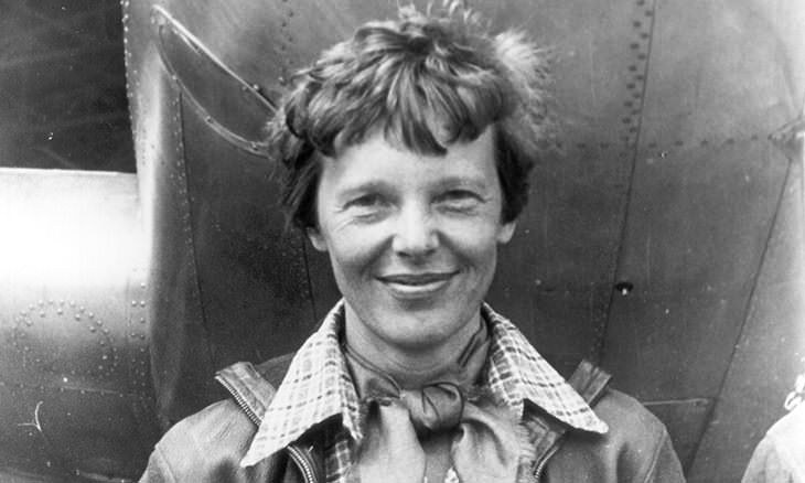  Amelia Earhart sonriendo junto a su avión