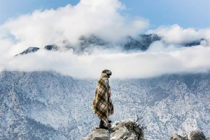 hombre envuelto en una manta delante de montaña nevada