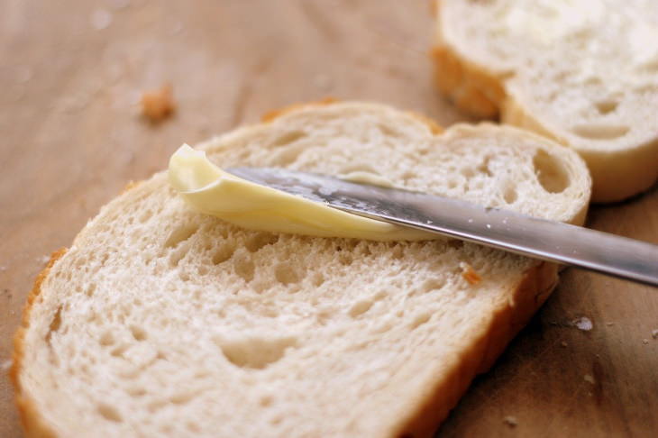  Mantequilla contra margarina mantequilla de pan blanco untada con cuchillo