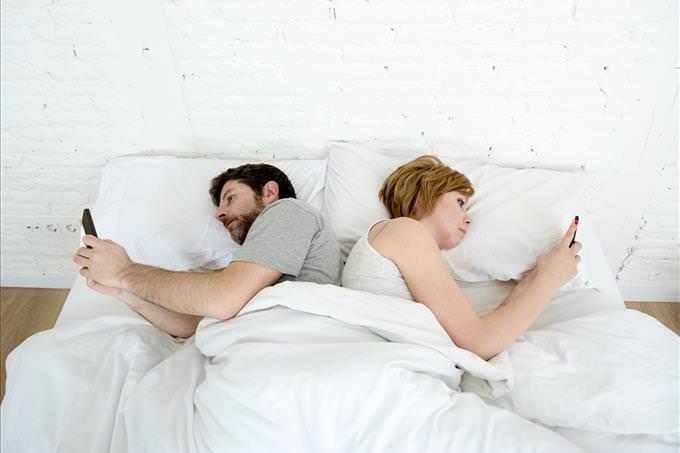 young couple in bed on their phones