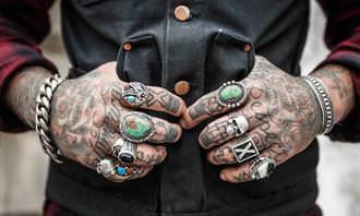 Find the differences: Man's tattooed hands with rings