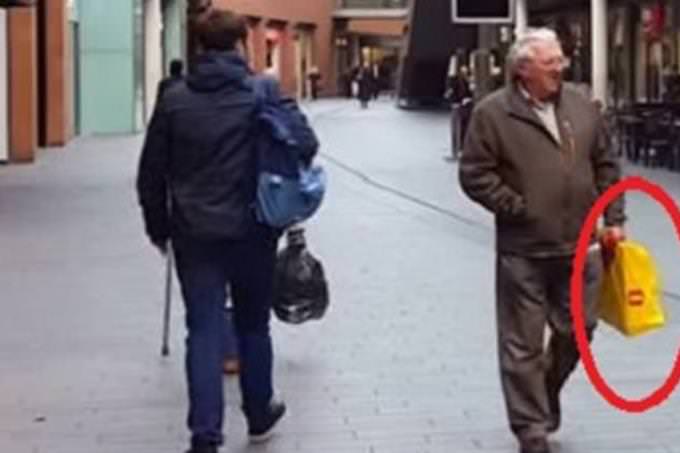Un anciano con una bolsa de compras amarilla y roja