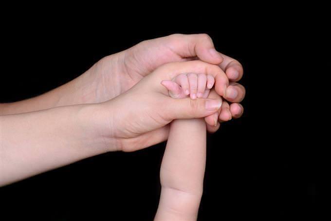 Woman's hand holding baby's hand