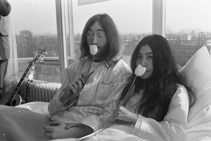 John Lennon and Yoko Ono sit with flowers