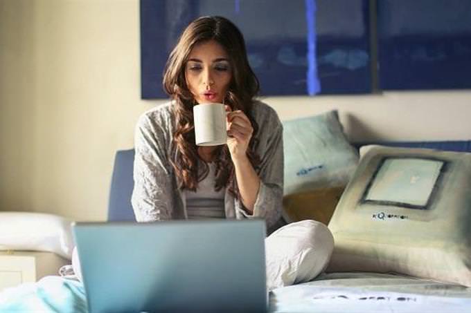 Mujer con una taza de café viendo una pantalla