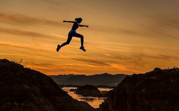 silhouette of woman jumping during sunset