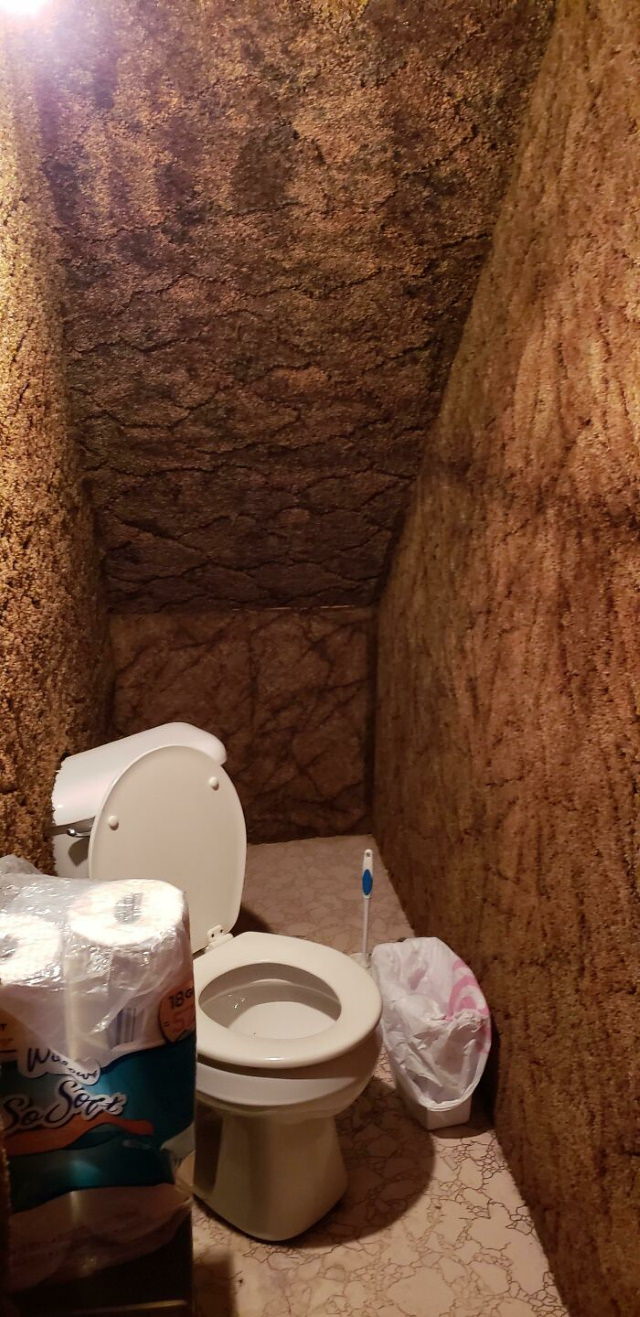 8. "El" baño "debajo de las escaleras de mi amigo" donde el inodoro está en diagonal y parcialmente instalado en la pared alfombrada "