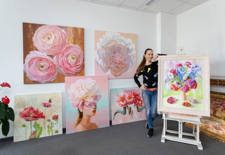 Pinturas Florales De Ira Volkova la artista posando con sus múltiples pinturas