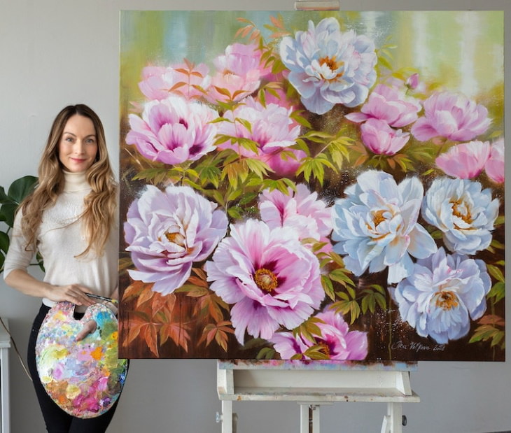 Pinturas Florales De Ira Volkova la artista posando con una pintura floral