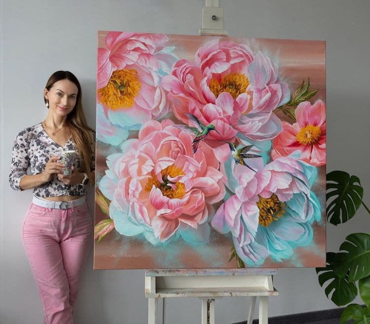 Pinturas Florales De Ira Volkova la artista posando con una pintura azul con rosa