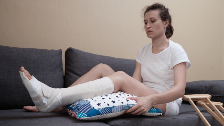 Mujer coloca su pierna fracturada sobre un cojín