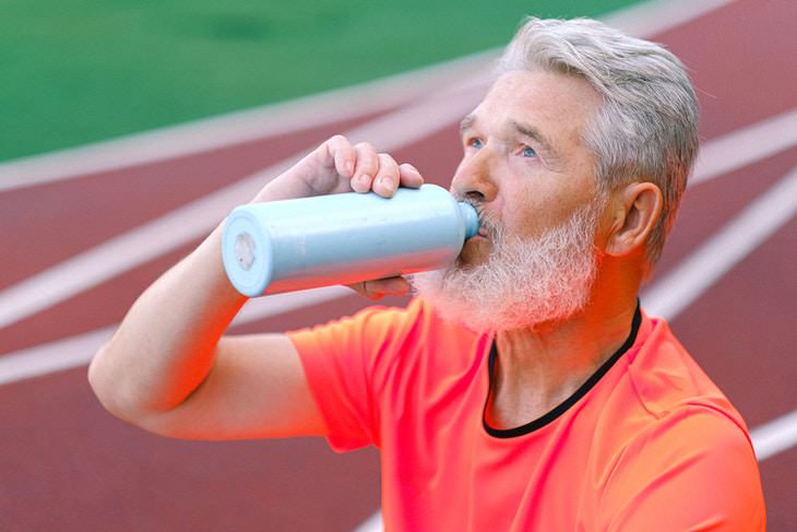 Rutina de caminata para personas mayores hombre bebiendo agua de un frasco