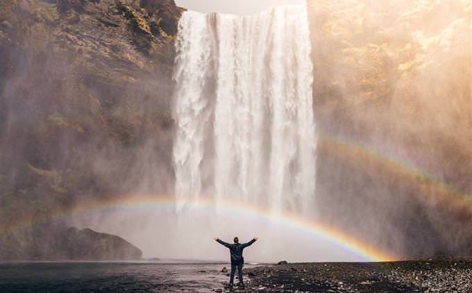 Cómo fluye tu vida: un hombre frente a una cascada con las manos en alto