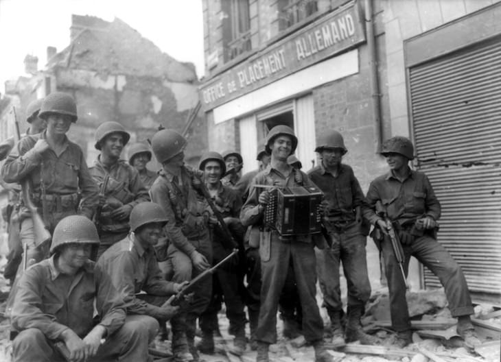 Fotos De Normandía De 1944 Tocando el acordeón frente a la oficina de colocación alemana, 20 de agosto de 1944