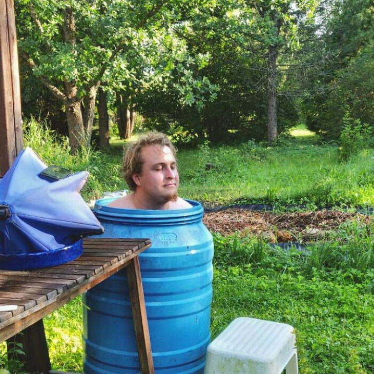 El hombre de la ola de calor sentado en un barril de agua