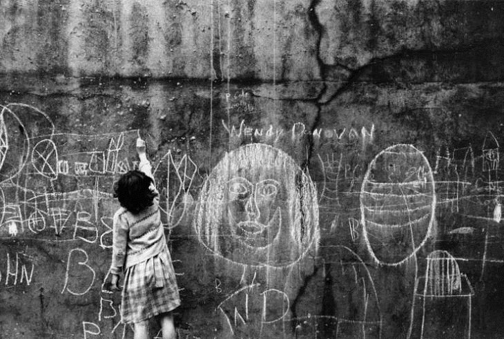 Niños Jugando En Las Calles De Londres Una niña dibuja con tiza en una pared