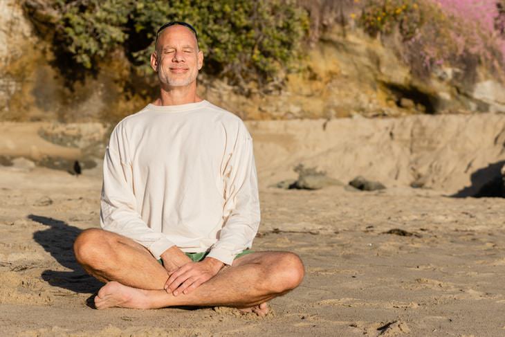 Ejercicios de respiración para perder peso hombre sonriente meditando en la playa