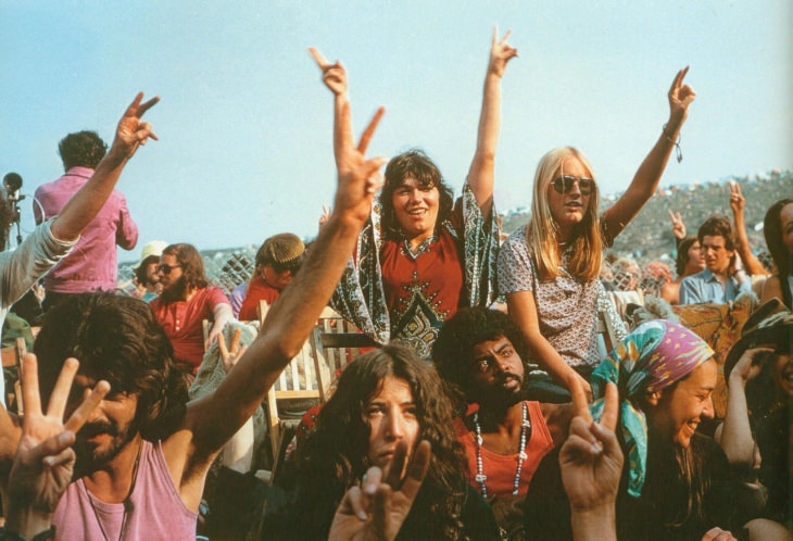 Gente de Woodstock en la multitud haciendo el signo de la paz 