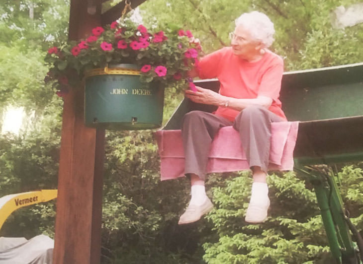 8. Esta asombrosa mujer de 96 años riega sus flores al ser levantada en un tractor.