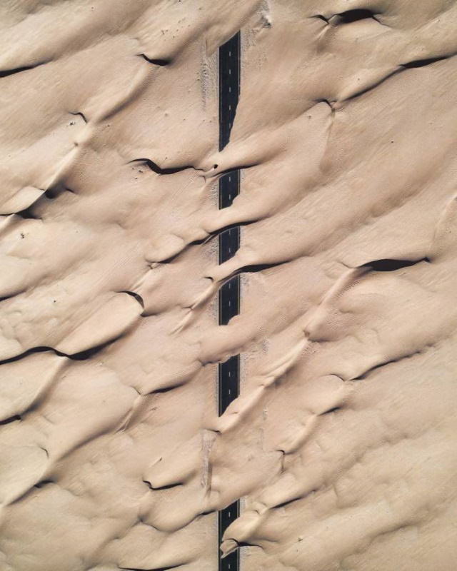 20 Asomborosas Fotografías  Una imagen aérea de una carretera parcialmente cubierta por la arena del desierto