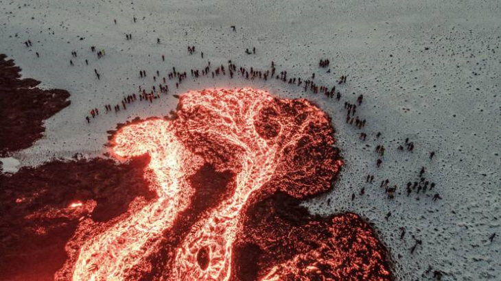 20 Asomborosas Fotografías Un grupo de personas reunidas alrededor de lava fundida en Islandia