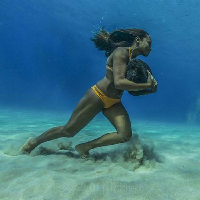 Historias Contadas Con Fotos Asombrosas La surfista profesional, Ha’a Keaulana, corriendo con una roca de 23 kg 