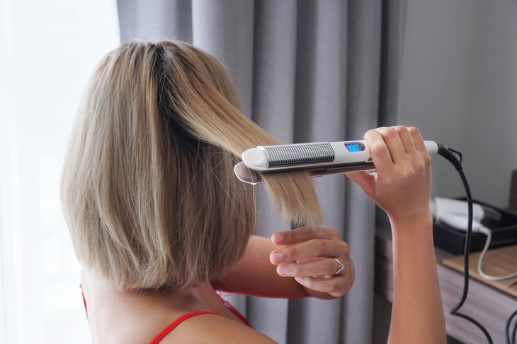 Consejos Para El Cabello Graso, Mujer alisándose el cabello