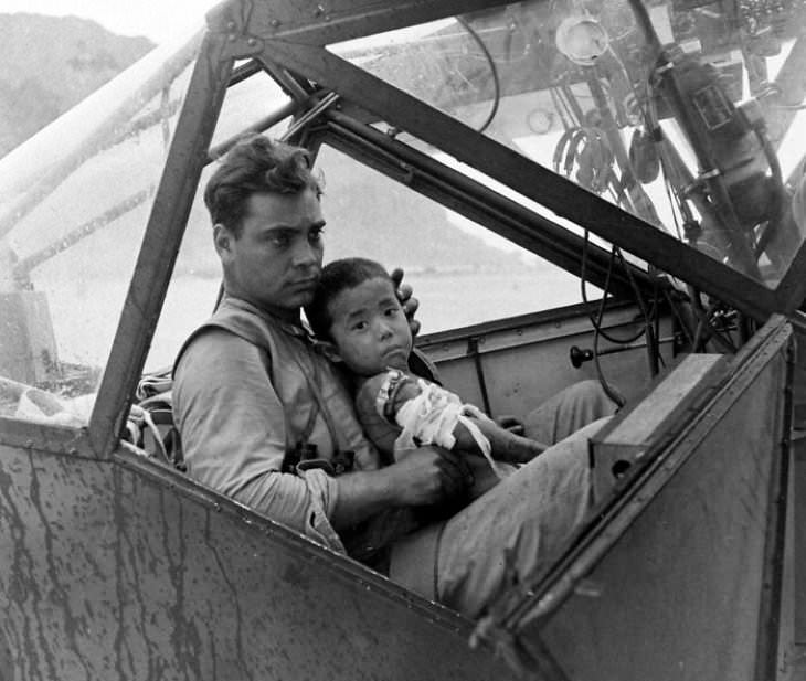 Fotos Eventos Históricos, Un soldado estadounidense acuna a un niño japonés herido y lo protege de la lluvia