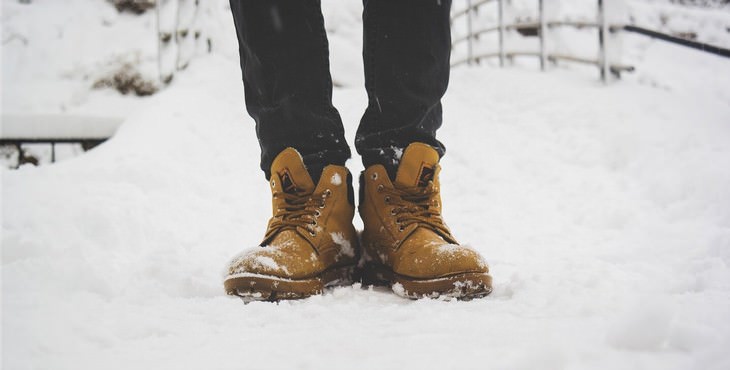 Cuidar Tu Césped En El Invierno, una persona pisando la nieve con sus botas