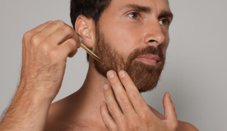 Psoriasis Facial, hombre aplicándose aceite en la barba