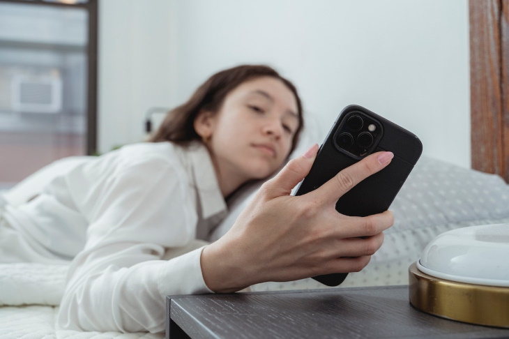 Sueño Bifásico, mujer despertando y viendo su teléfono móvil