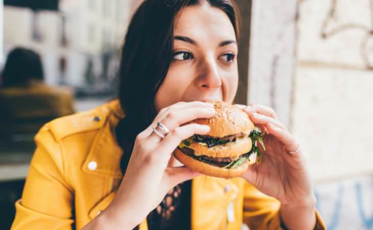 ¿Por Qué Nos Encanta La Comida Crujiente? Mujer comiendo una hamburguesa