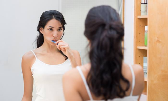 Pasta De Dientes Con Fluoruro vs Sin Fluoruro, mujer cepillándose los dientes