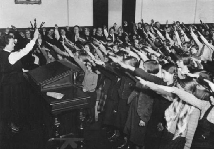 Momentos Históricos Capturados En Fotos, En una escuela primaria en Berlín, los estudiantes rinden homenaje al entonces líder nazi Adolf Hitler, en 1934.