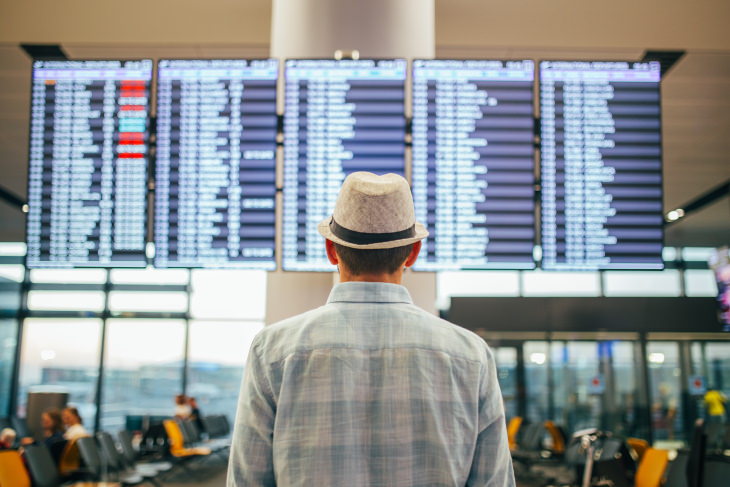 Retraso en el vuelo, hombre con sombrero en el mostrador del aeropuerto