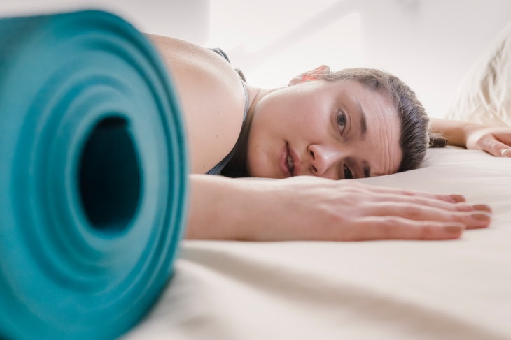 Mitos sobre el estreñimiento mujer cansada junto a la esterilla de yoga
