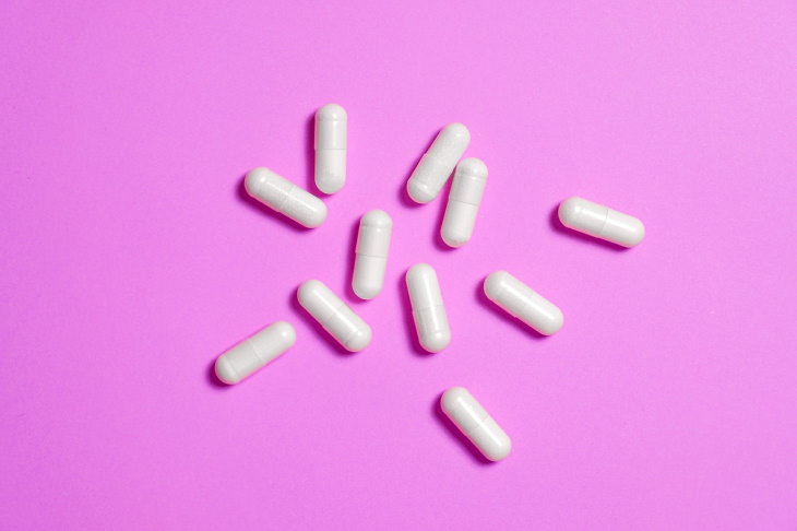 cápsulas de suplementos innecesarios sobre un fondo rosa
