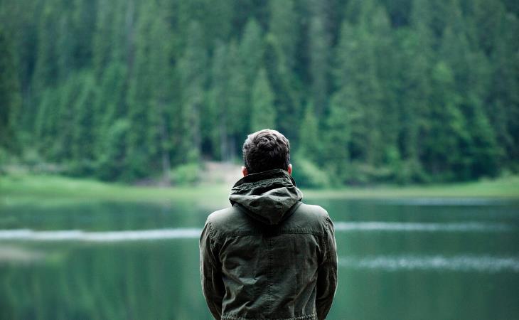 Beneficios Del Silencio Para La Salud, hombre sentado en un lago