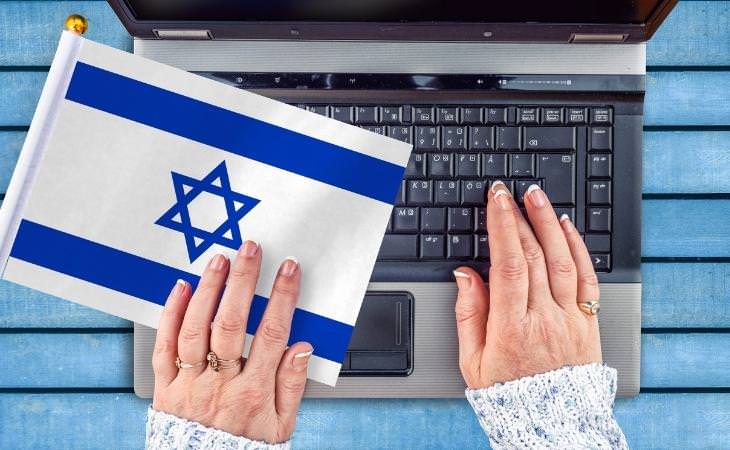 La alta tecnología israelí: una mano sobre un teclado portátil con una bandera israelí al lado
