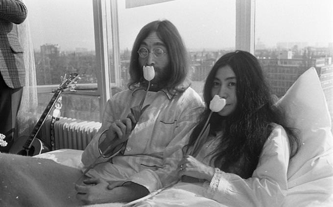 John Lennon y Yoko Ono sit with flowers