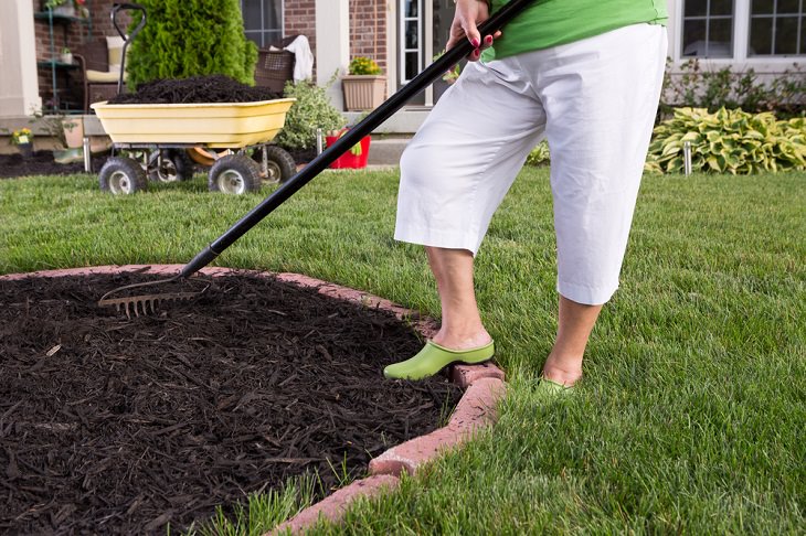Mejoras Para Tu Hogar En Otoño, mujer agrega mantillo a su jardín