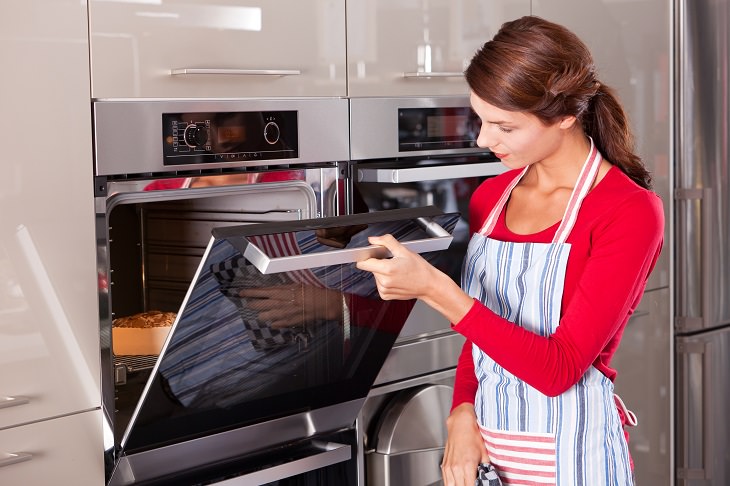 Errores De Cocina, mujer revisa pastel en el horno