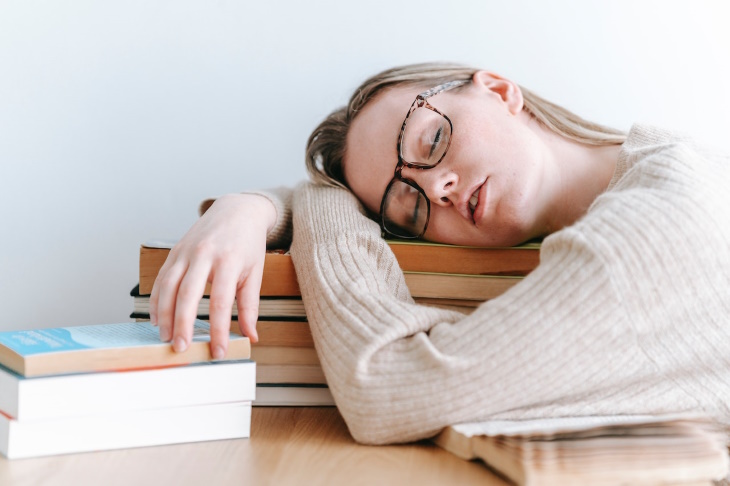 Síndrome de burnout, mujer durmiendo sobre unos libros